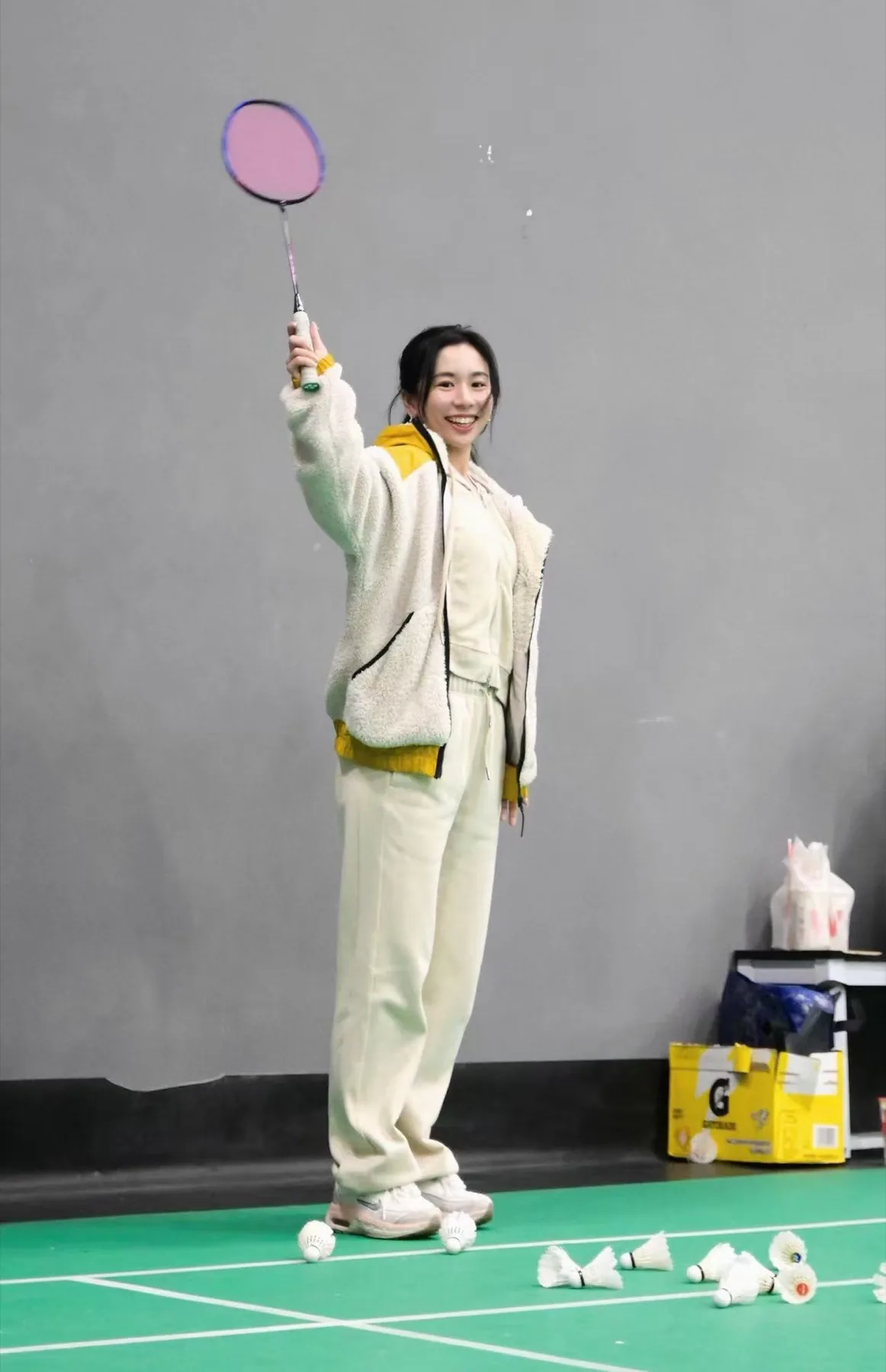 田鸡酱举起球拍，在球场上微笑